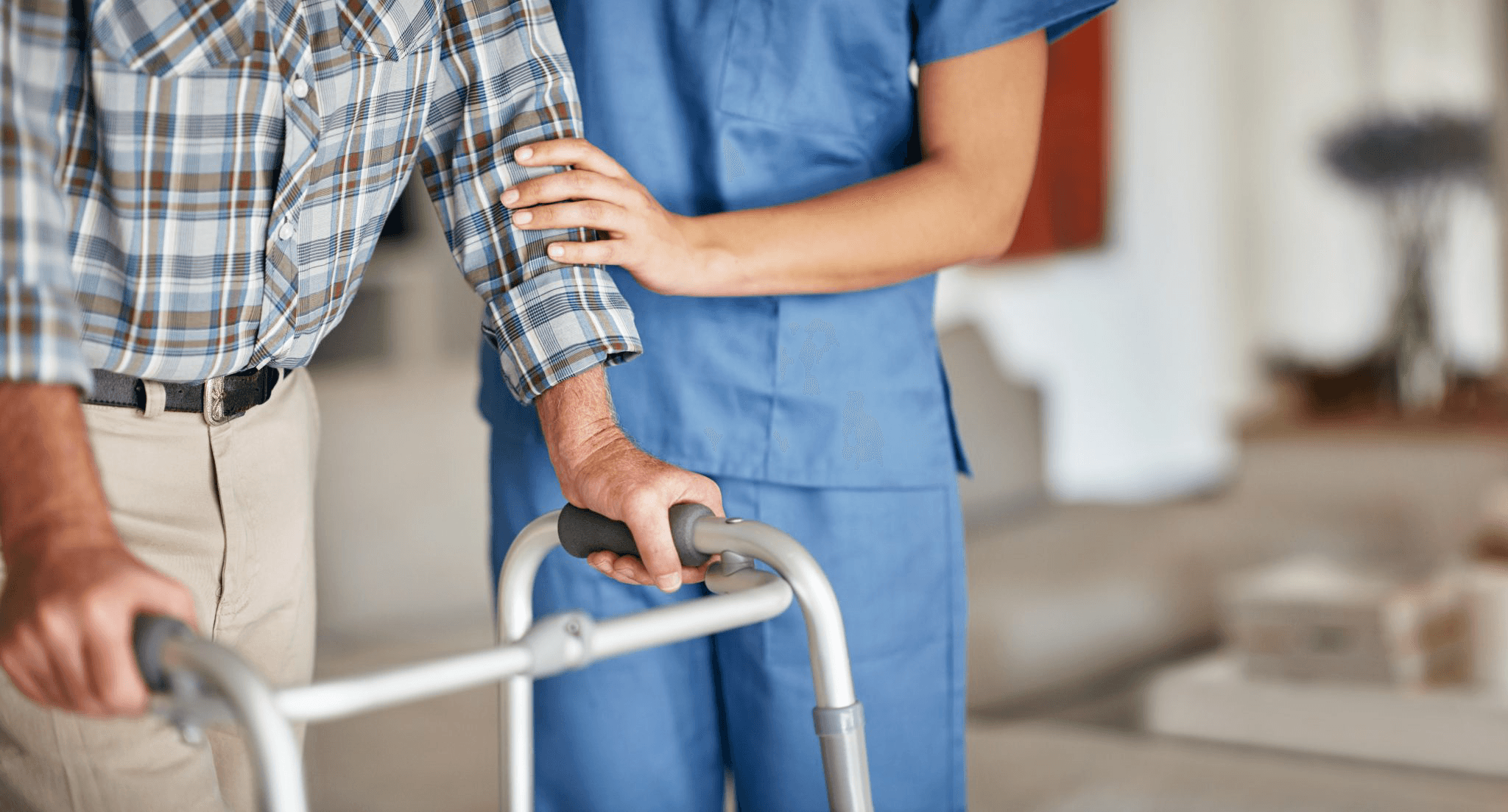 Care worker helping someone walk with a zimmer frame